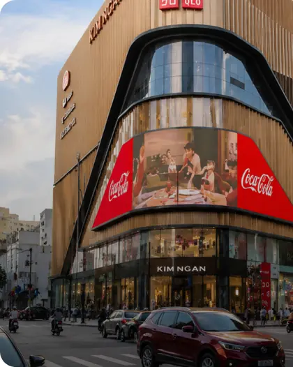Curved Coca-Cola LED billboard on a shopping mall corner in Vietnam