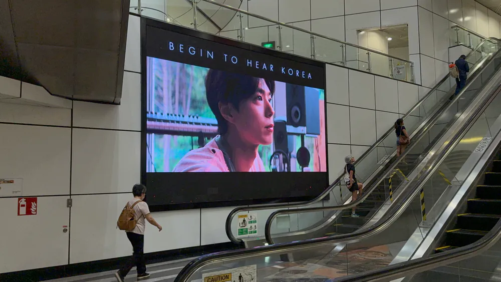 Korea Tourism ad on a large indoor LED screen beside escalators in Singapore