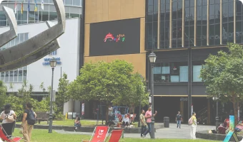 LED screen on a building beside a public lawn with passing pedestrians